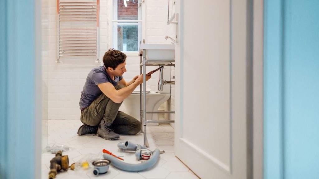 Man fixing a leak under the bathroom sink